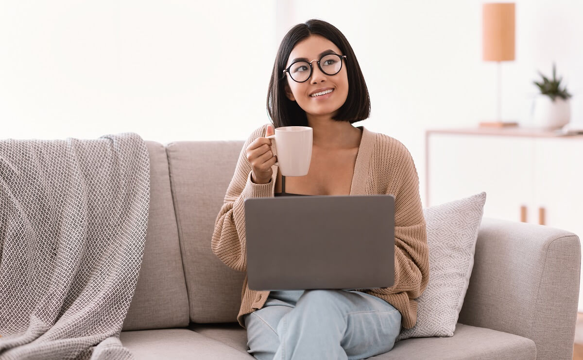 Young asian woman using laptop and drinking coffee