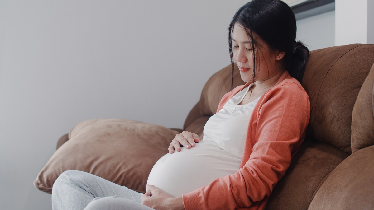 Young Asian Pregnant woman holding her belly talking with her ch